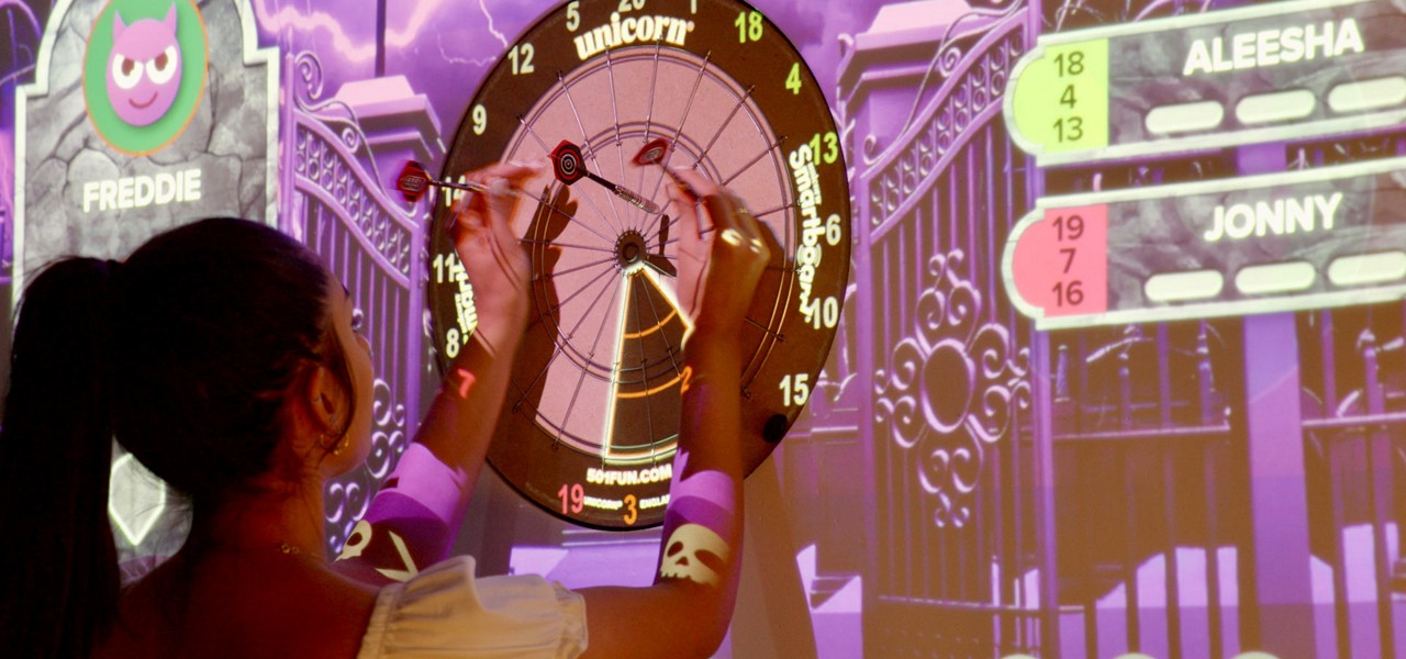 Woman playing darts on a projected darts board.