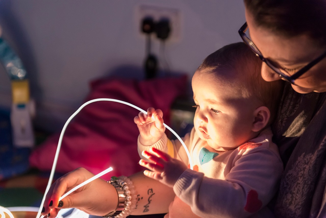 Baby exploring glowing sensory toys.