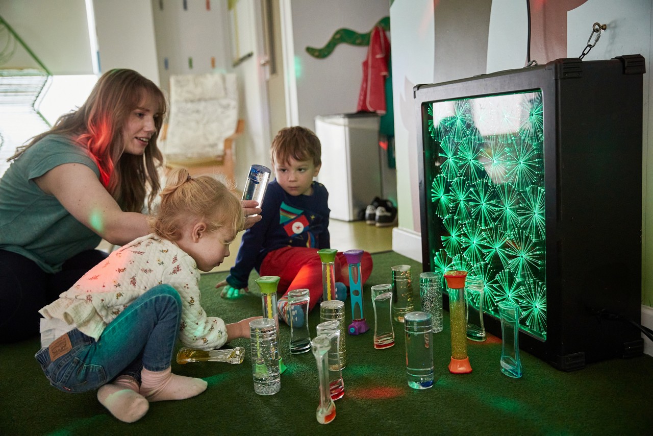 Two young children exploring objects with colourful lights.