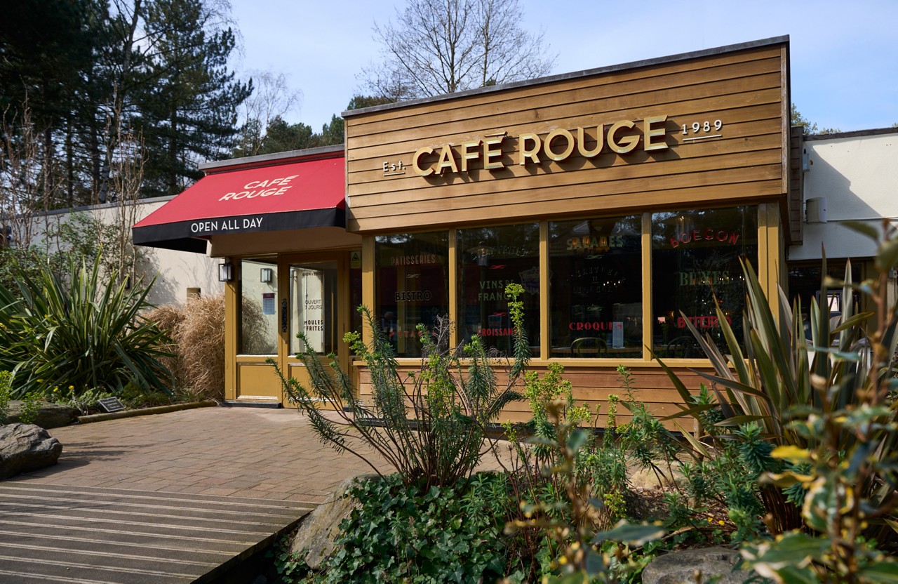 Exterior of Cafe Rouge at Sherwood forest with wooden path leading up to the building and green plants on either side of path