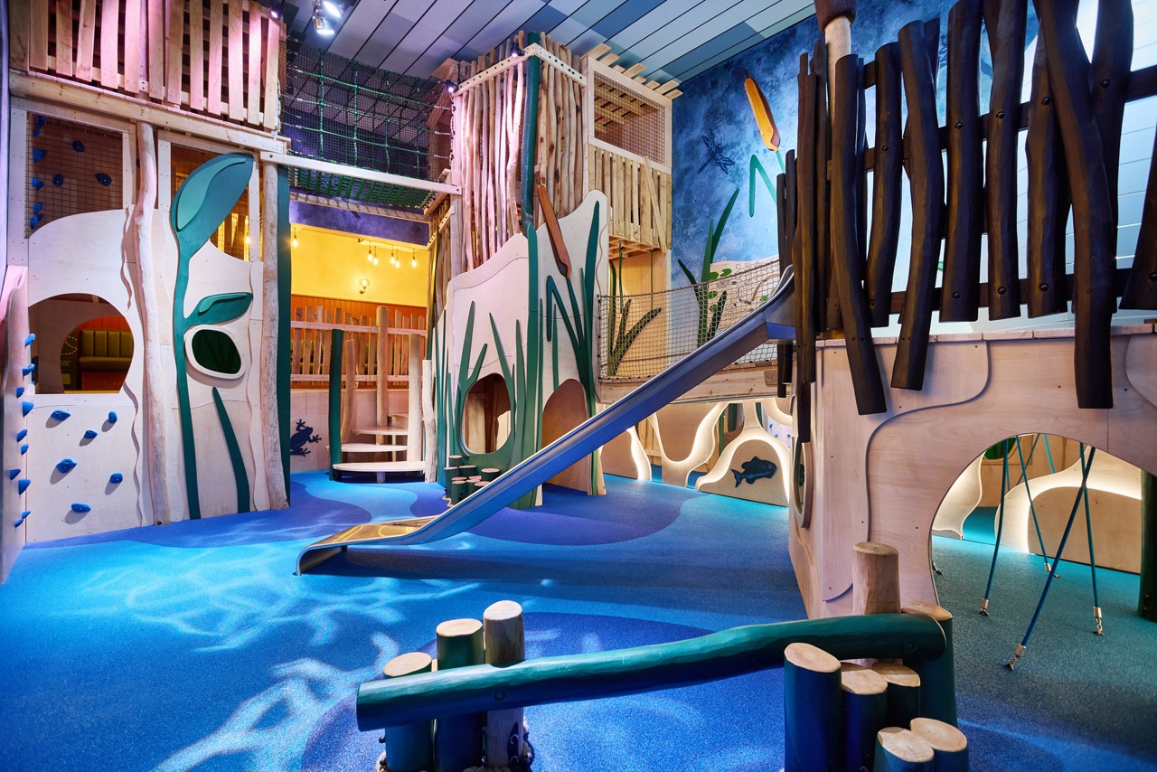 Soft play area with a slide, blance beams and climbing walls.
