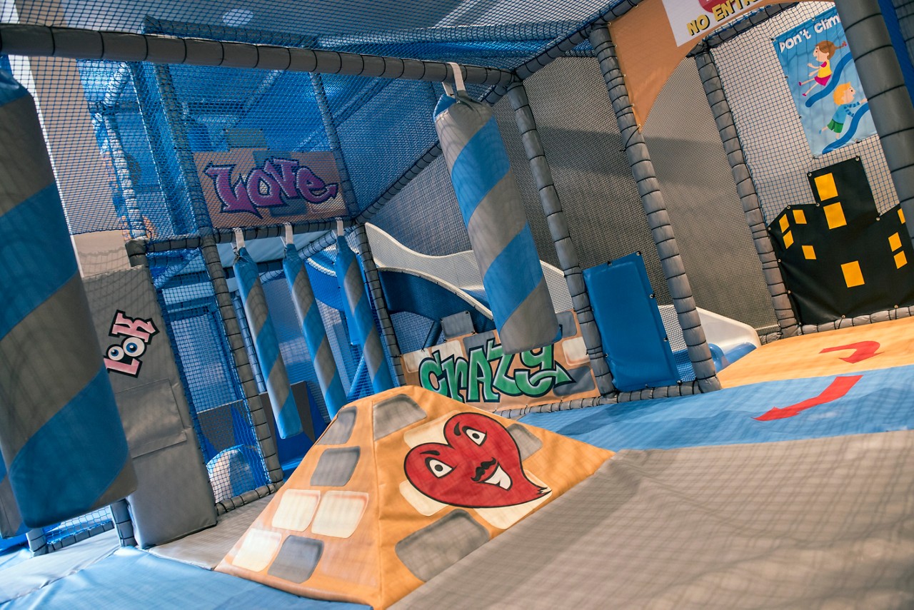 A little girl sat on her Dad's knee colouring in a picture at the table. 