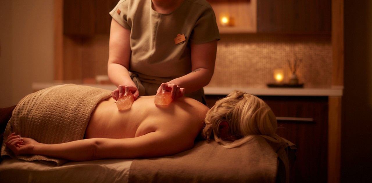 Woman having salt blocks placed on her back.