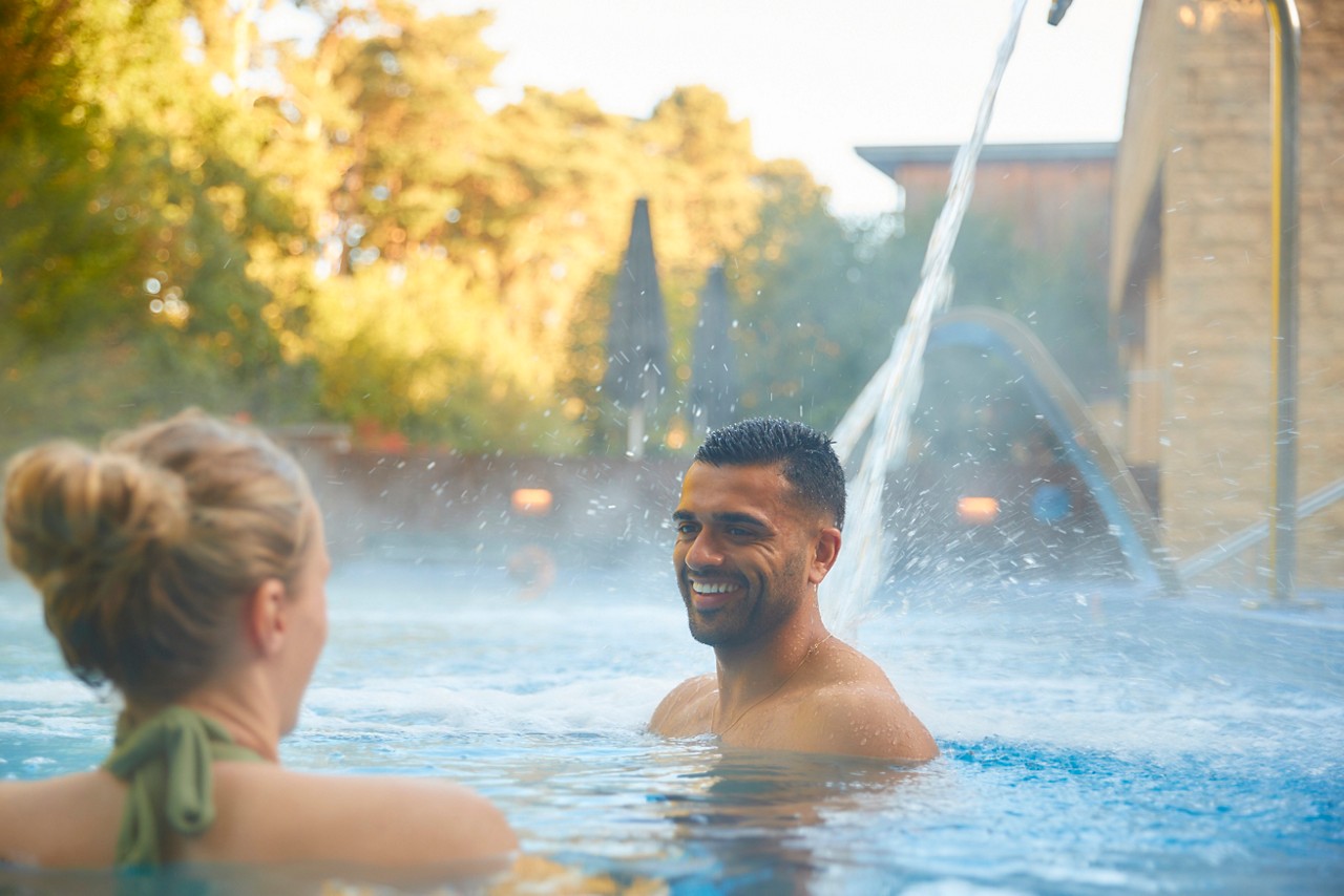 Man and woman soaking under flowing water.