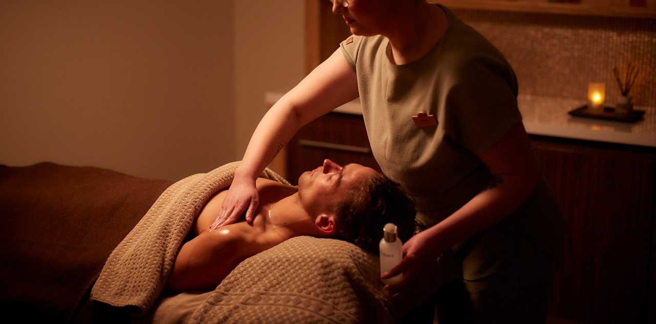 Woman applying products to a persons shoulders.