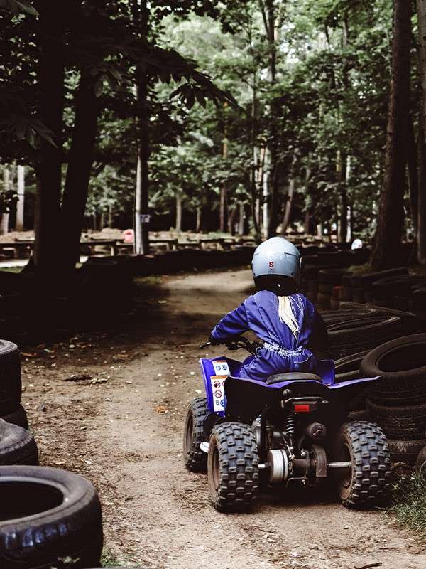 A child on a quad bike riding through the forest.